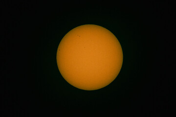 Tarcza słoneczna sfotografowana z użyciem teleobiektywu. W wyniku zastosowania filtra optycznego uzyskano ciepłą barwę tarczy słonecznej. Widoczne są plamy na powierzchni słońca. - obrazy, fototapety, plakaty