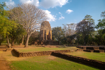 Fototapeta na wymiar The ruins of an old castle built with laterite bricks of the ancient city of Si Thep..Ancient Angkor Temple Tower Amidst Park's Historic Stone Ruins and Towering Trees .in Si Thep Historical Park.