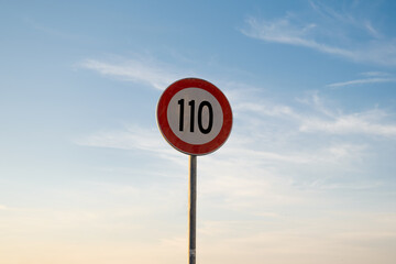 110 miles km maximum speed limit traffic sign isolated with sunset sky