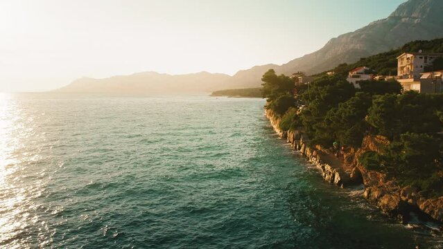 Rocky coastline in Makarska Riviera Croatia. Biokovo mountain at sunset. Warm glow of the evening sun with azure waters of the Adriatic Sea.