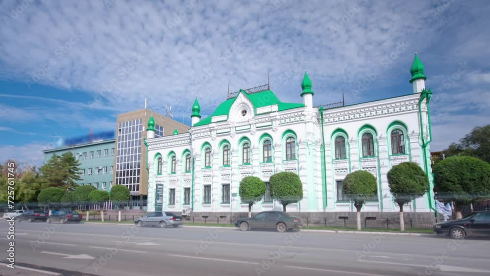 Wall mural 18th Century Building Timelapse Hyperlapse in the Heart of Uralsk. Summer Day Traffic Flows Beneath a Blue Cloudy Sky, Accentuating the Historic Charm of Western Kazakhstan