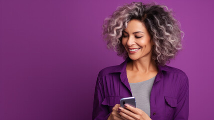 Content mature female with grey colored hair portrait with smartphone against purple in studio.