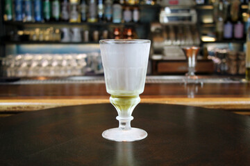 Glass with absinth on bar interior background close-up.