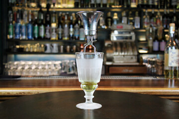 Classic type of absinthe preparation with brouiller (a tool for preparing absinthe). Glass with...