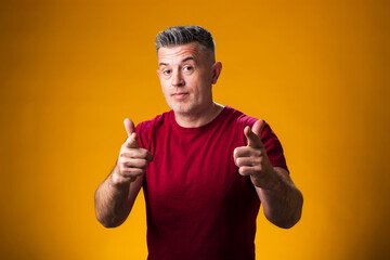 Fototapeta premium Smiling man pointing fingers at camera over yellow background.