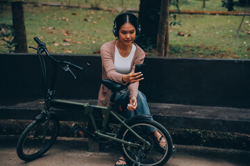 Obraz premium Happy young Asian woman while riding a bicycle in a city park. She smiled using the bicycle of transportation. Environmentally friendly concept.