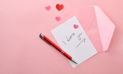 Romantic note on pink background with pink envelope and pen