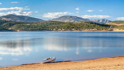 expedition canoe on a sandy beach of Carter Lake in northern Colorado, warm winter afternoon - obrazy, fototapety, plakaty
