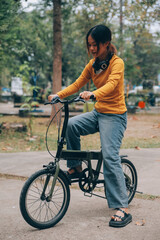 Happy young Asian woman while riding a bicycle in a city park. She smiled using the bicycle of transportation. Environmentally friendly concept.