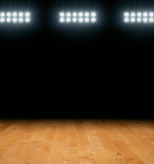 Maple basketball floor with dark background below arena lights