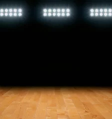 Maple basketball floor with dark background below arena lights © Daniel Thornberg