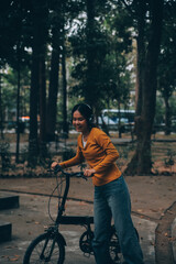 Obraz premium Happy young Asian woman while riding a bicycle in a city park. She smiled using the bicycle of transportation. Environmentally friendly concept.