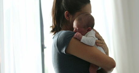 Candid mom holding newborn baby hugging and loving
