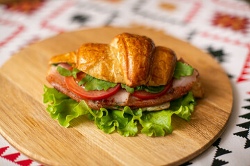 Croissant filled with bacon and tomatoes on a wooden background