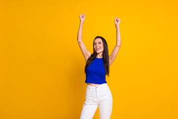 Fototapeta na wymiar Photo of cheerful lucky woman wear blue top rising fists empty space isolated yellow color background
