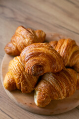 Croissant on a wooden plate on a wooden background