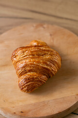 Croissant on a wooden plate on a wooden background