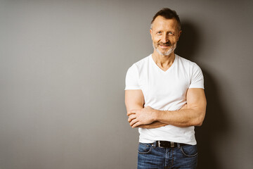 Smiling Senior Man in White T-Shirt Standing Against Brown Wall with Copy Space - 725802159