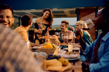 Happy woman serving food to her friends at dining table on patio.
