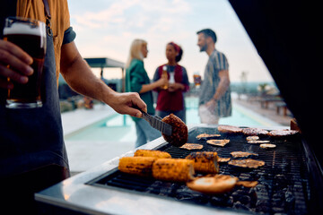 Close up of man making barbecue at poolside party in backyard. - Powered by Adobe
