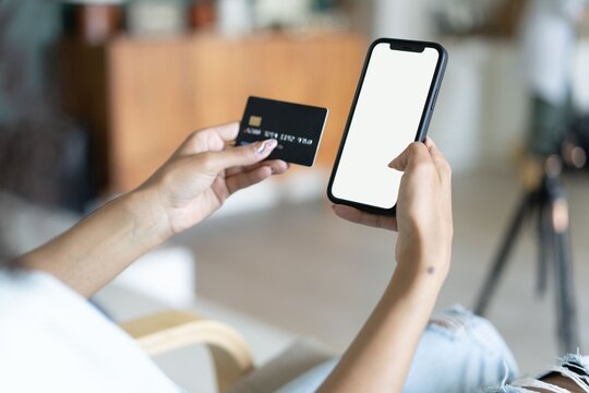 A close-up photo of a young woman using her smartphone and her credit card at home. Online shopping ( credit card mockup ).