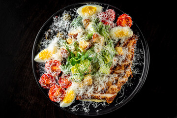Caesar salad with croutons, cheese, eggs, tomatoes and grilled chicken on wooden table