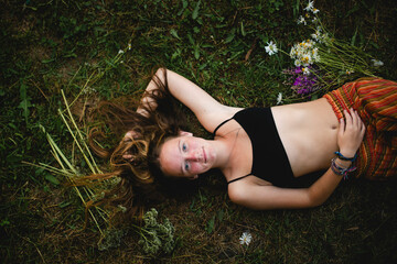 A girl lies on the grass with her long hair in the countryside.