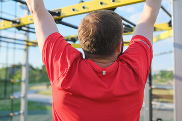 man from behind doing pull ups outdoor, street workout, active lifestyle, healthy routine, male health concept