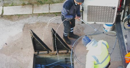 Nodugno, Italy - 20 june 2021: telecommunication technician proceeds with the cabling of fibre optic cables. In particular, individual fibre optic cables are pulled out of the protective sheathing