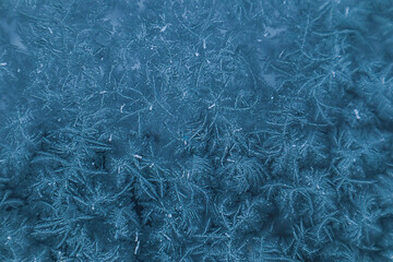 Frosty pattern in blue tones on window glass on a winter day