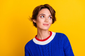 Photo portrait of pretty young girl look interested empty space wear trendy blue knitwear outfit isolated on yellow color background