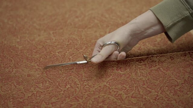 This video shows fancy red and gold upholstery fabric being cut by sewing sheer scissors. 