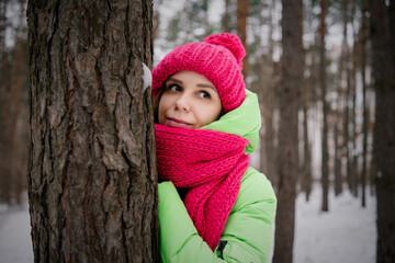 Woman in Green Jacket and Pink Scarf Leaning Against a Tree