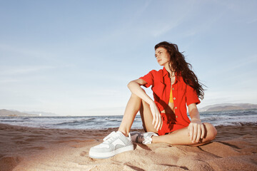 Fototapeta na wymiar Smiling Woman in Trendy Beach Fashion, Sitting on Sand: Summer Emotion