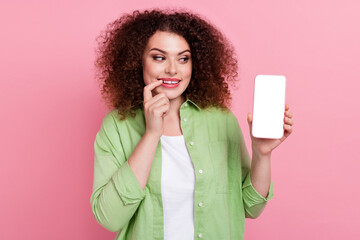 Photo portrait of pretty young girl hold device white screen look interested wear trendy green outfit isolated on pink color background