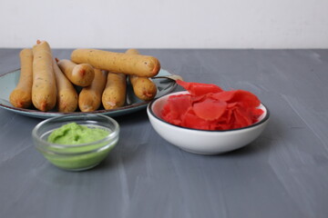 Red pickled ginger and spicy green wasabi sauce. Spicy sauces for meat on grey background with metos for copyspace text
