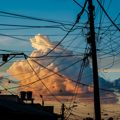 A beautiful large cloud imprisoned by the meshes of a tangle of electrical cables at sunset....