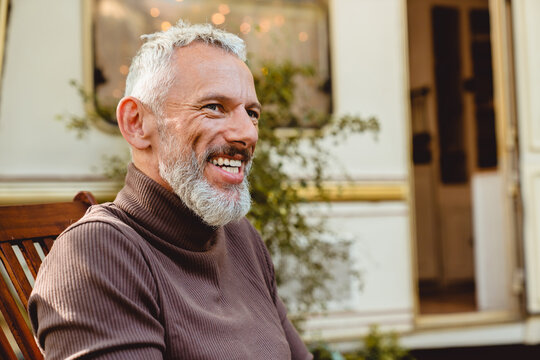 Cropped Side View Portrait Of A Good-looking Smiling Aged Man Having A Break On Deck Chair Near The Van. Solo Traveler Adventurer Explorer On A Trip By Trailer Motor Home