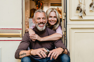 Hugging happy caucasian couple spouses travelers explorers adventurers sitting in the doorway of...