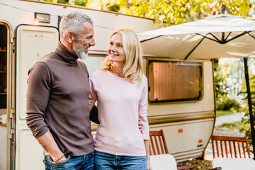 Happy mature caucasian couple looking at each other with passion and love near their caravan home....