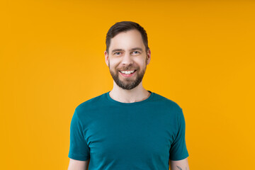 Close up studio shot of young attractive smiling bearded man posing over bright colored orange...