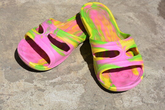 Women's summer shoes are arranged on a cement background. Pink, bright, multi-colored flip-flops made of rubber for leisure and the beach.