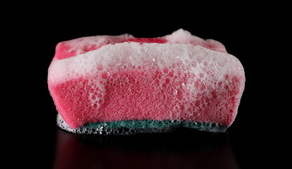 Soap foam with bubbles and red sponge isolated on black, side view
