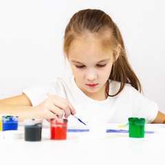 Portrait of a girl painting during an art class on at table indoors, additional drawing courses.