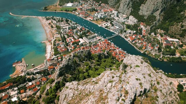 Coastal Town Omis on Rocky Landscape. Red-roofed buildings along the turquoise Adriatic Sea. Starigrad Fortress in Split-Dalmatia, Croatia.