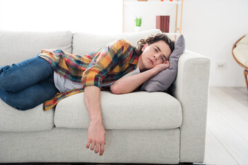 Photo of stressed depressed guy wear plaid shirt lying couch feeling apathy indoors room home house