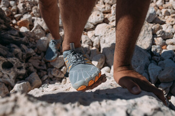 Protective swimming shoes on men's feet.  Close-up. Men's feet in stylish sports water slippers on the rocky seashore.