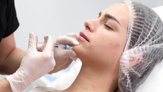 Injection procedure. The cosmetologist slowly and carefully injects filler into the client’s chin. Advertising concept for facial care, youth and beauty