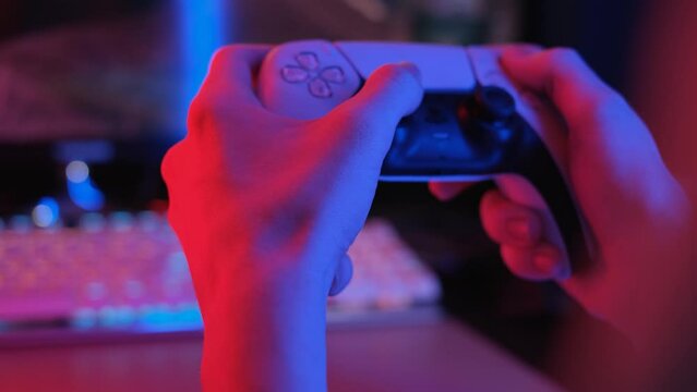 Joystick from a game console in the hands of a gamer in neon light, close-up