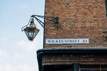 Street name sign on a building on Wilkes Street in London, UK. © Alena